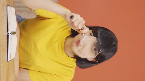 Vertical-video-of-Young-woman-looking-at-camera-with-magnifying-glass.